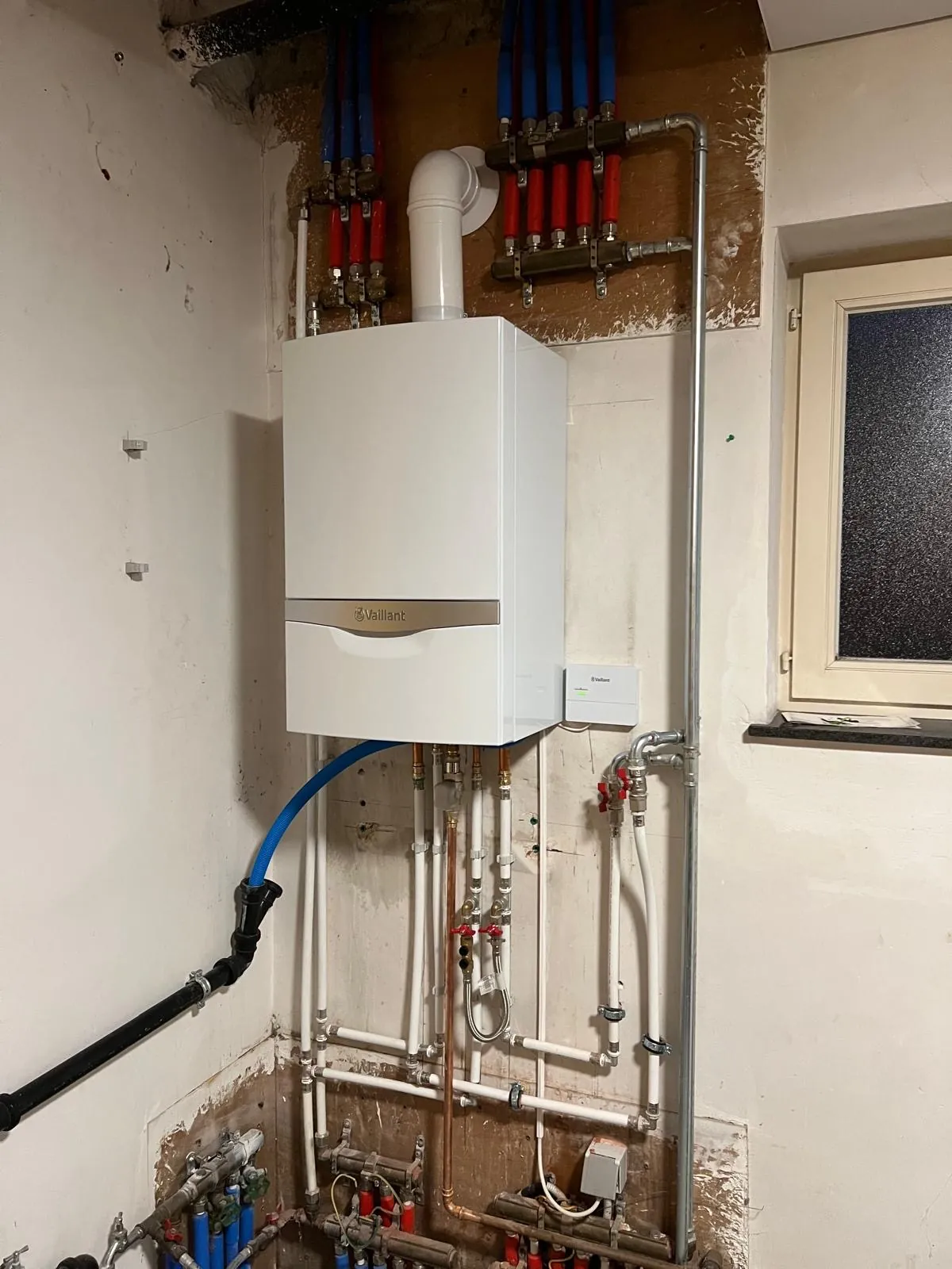 Vervangen gasketel met rode en blauwe collectoren voor verwarming en sanitair, werk van HS Concept in Aalst