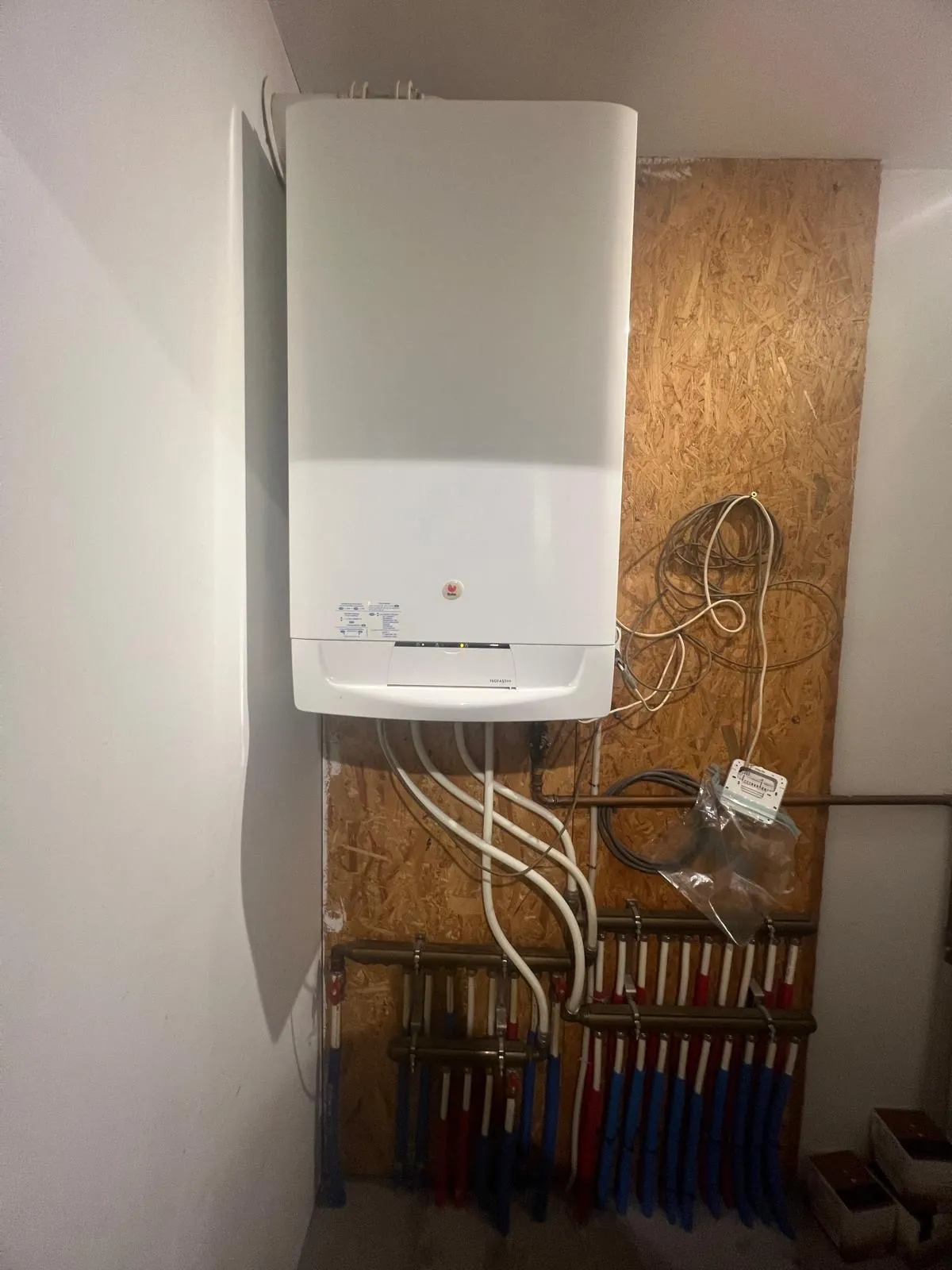 Gasketel met verdelers voor verwarming en sanitair op een technische wand, geplaatst door HS Concept in Aalst
