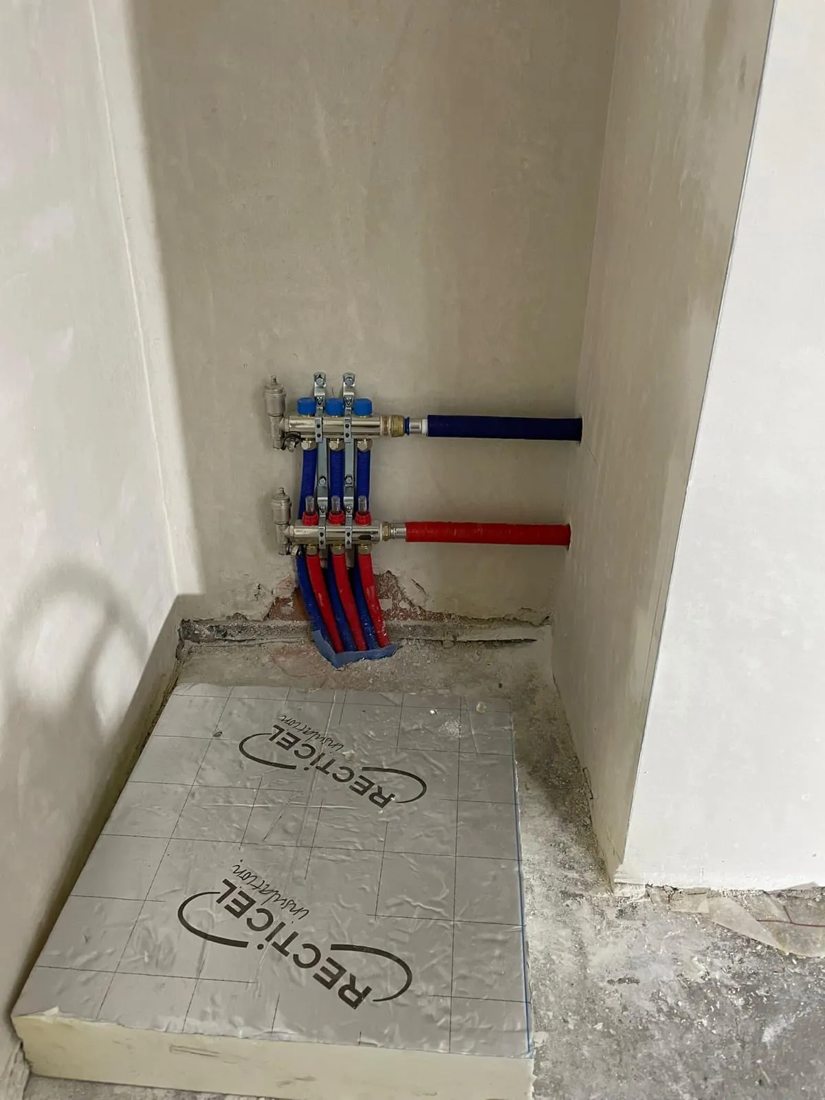 Collector voor vloerverwarming met aan- en afvoerleidingen op de isolatieplaten, geplaatst door HS Concept in Aalst