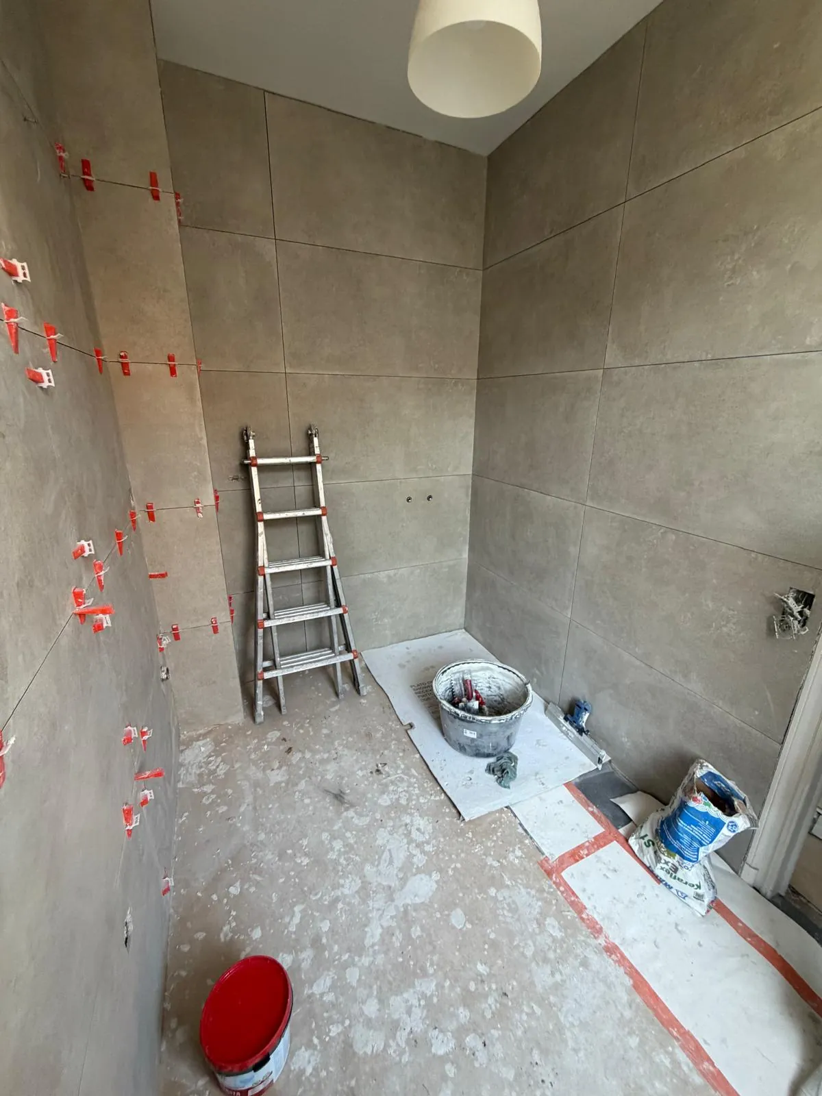 Grote wandtegels geplaatst in een badkamer in opbouw tijdens een renovatie door HS Concept in Aalst