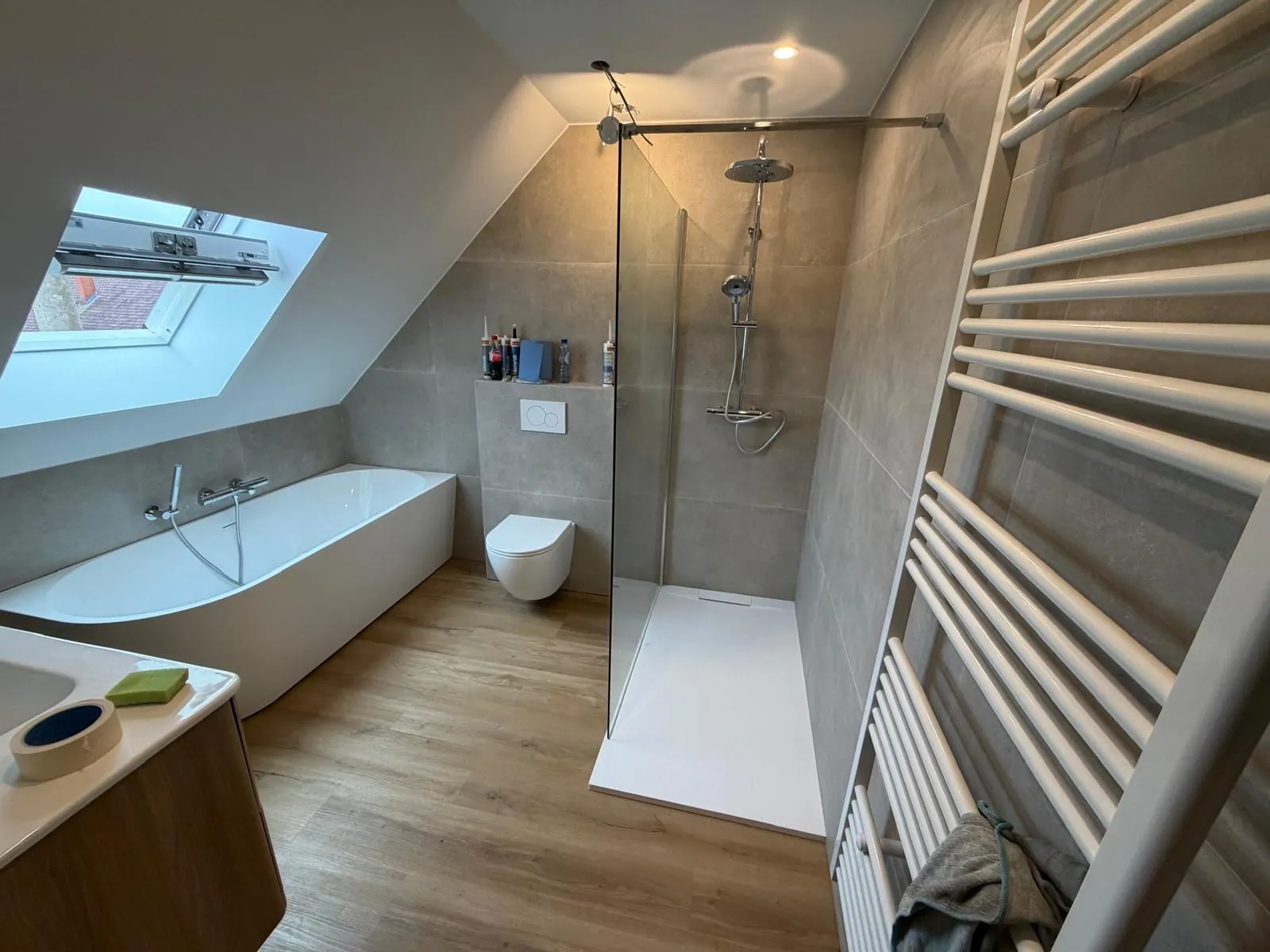 Badkamer op zolder met ligbad, inloopdouche, hangtoilet en handdoekradiator, geplaatst door HS Concept in Aalst