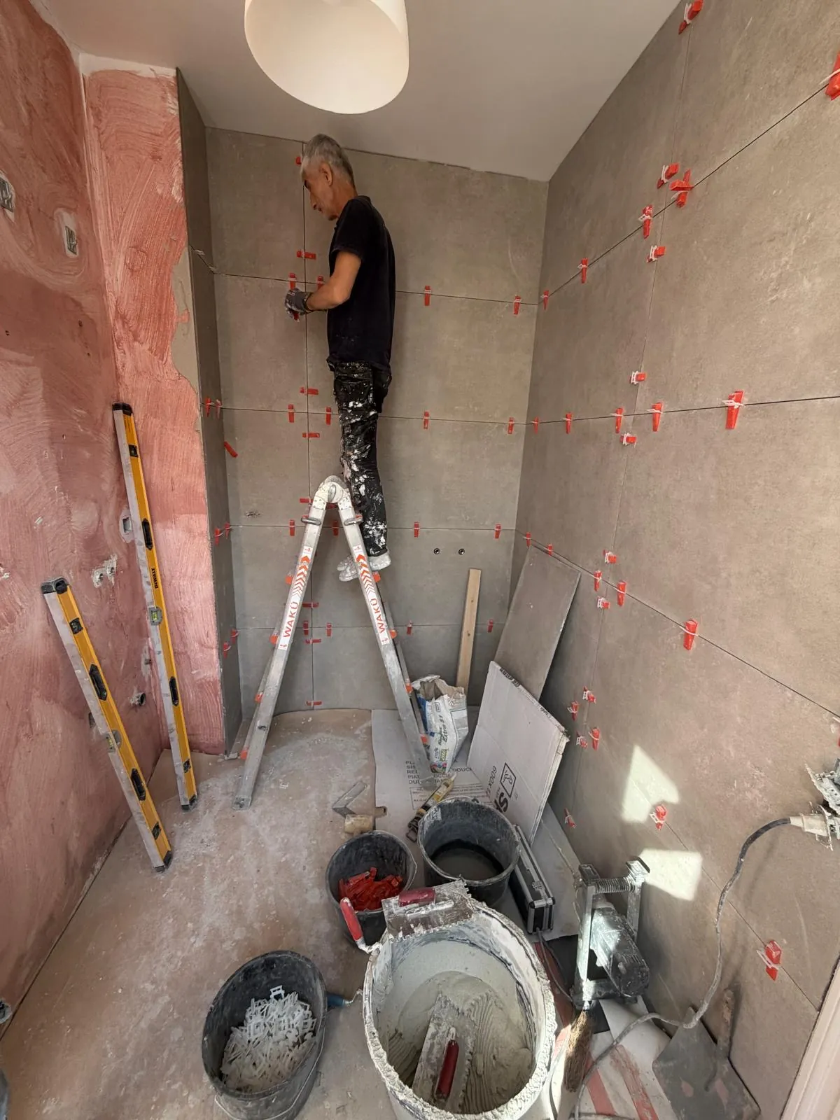 Tegelzetter plaatst grote wandtegels in een badkamer in renovatie bij HS Concept in Aalst